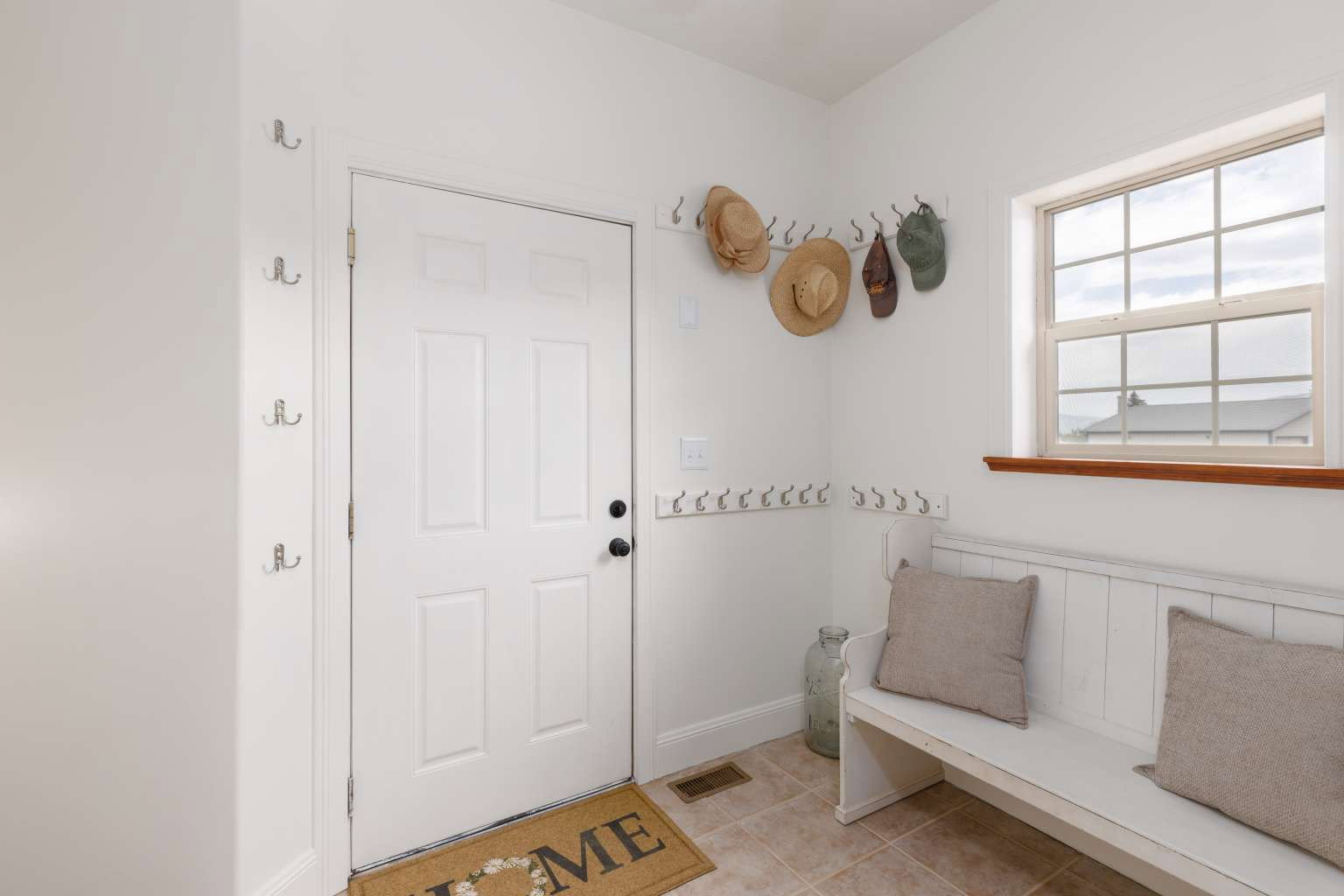 Entryway featuring a white paneled door with black hardware, ceramic tile flooring, and a window with wood trim