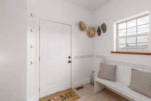 Entryway featuring a white paneled door with black hardware, ceramic tile flooring, and a window with wood trim
