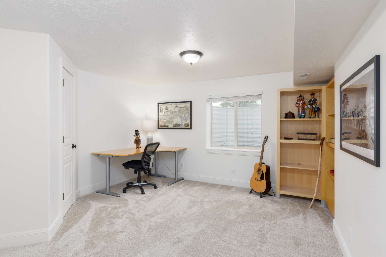 Carpeted room featuring a single window, built-in shelving, a panel door, and white baseboards