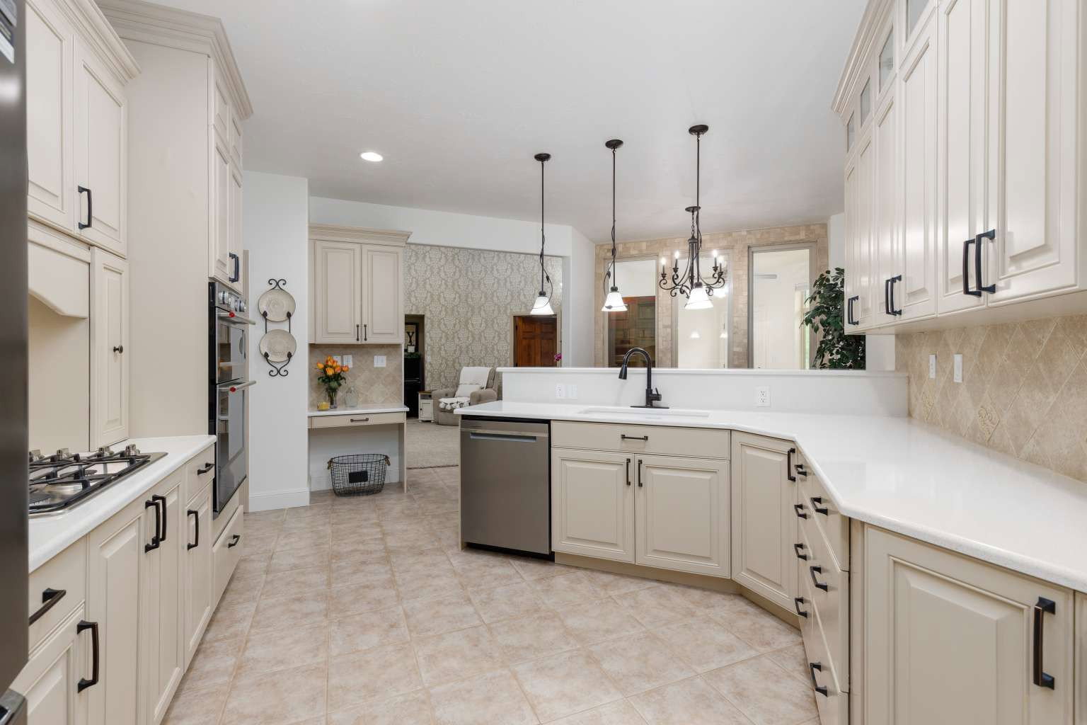 Kitchen featuring light-toned cabinetry with dark hardware, a gas cooktop, built-in double ovens, and a tile backsplash