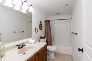 Bathroom featuring a wood-finish vanity with a built-in sink, a full-width mirror, and a coordinated shower-tub combination