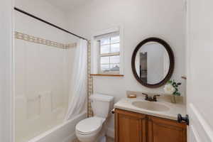 Bathroom featuring a full tub/shower combination with decorative tile surround, single vanity with wood-finish cabinetry, and a framed circular mirror