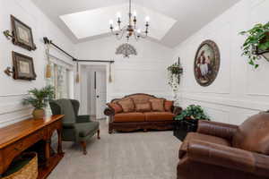 Interior living space featuring vaulted ceilings with a skylight, a chandelier, and wainscoting