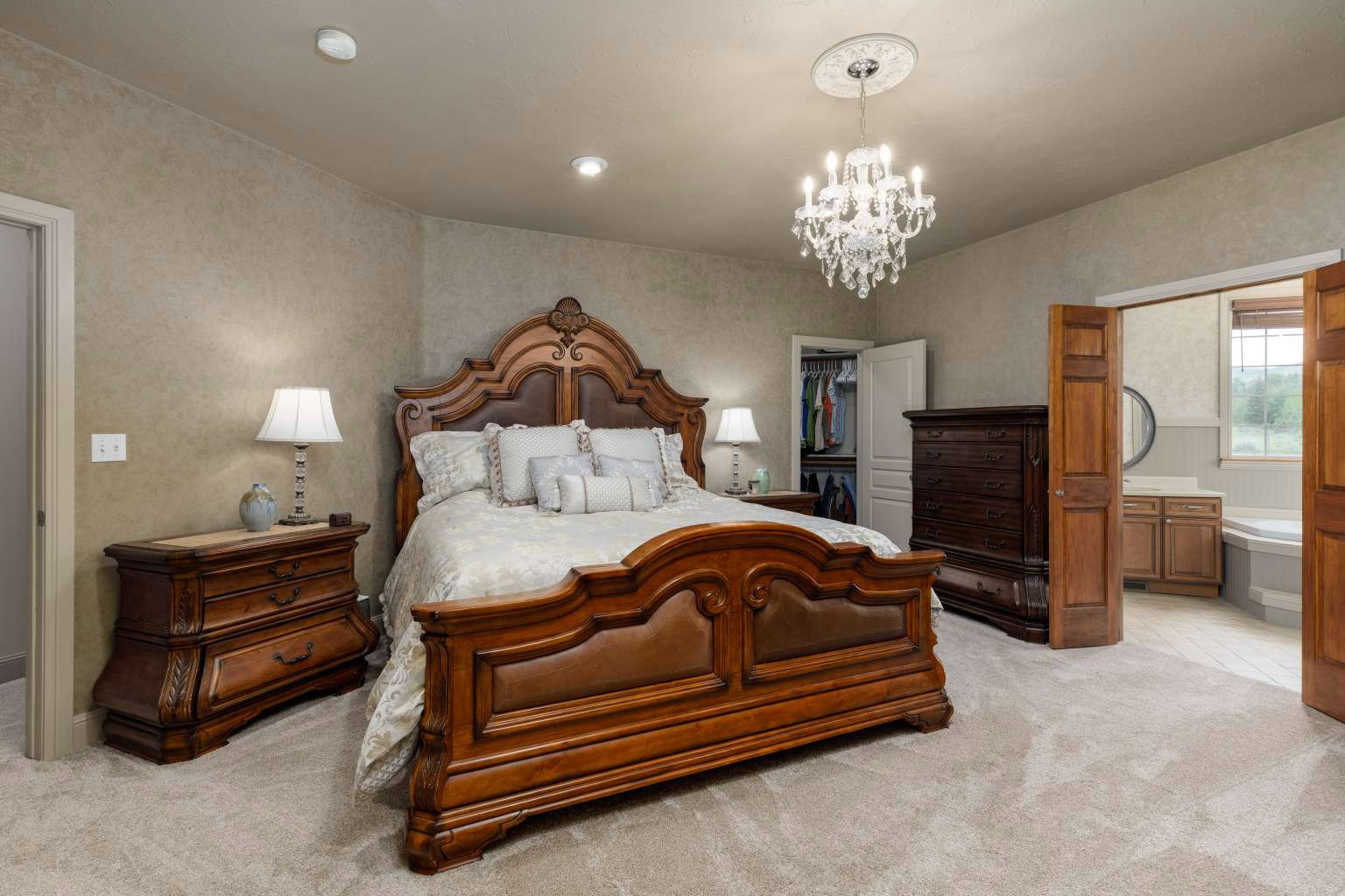 Spacious bedroom featuring neutral textured walls and light-colored carpet flooring