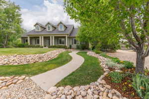 Ranch-style residence featuring a covered front porch with white columns, dormer windows, and a light green siding exterior
