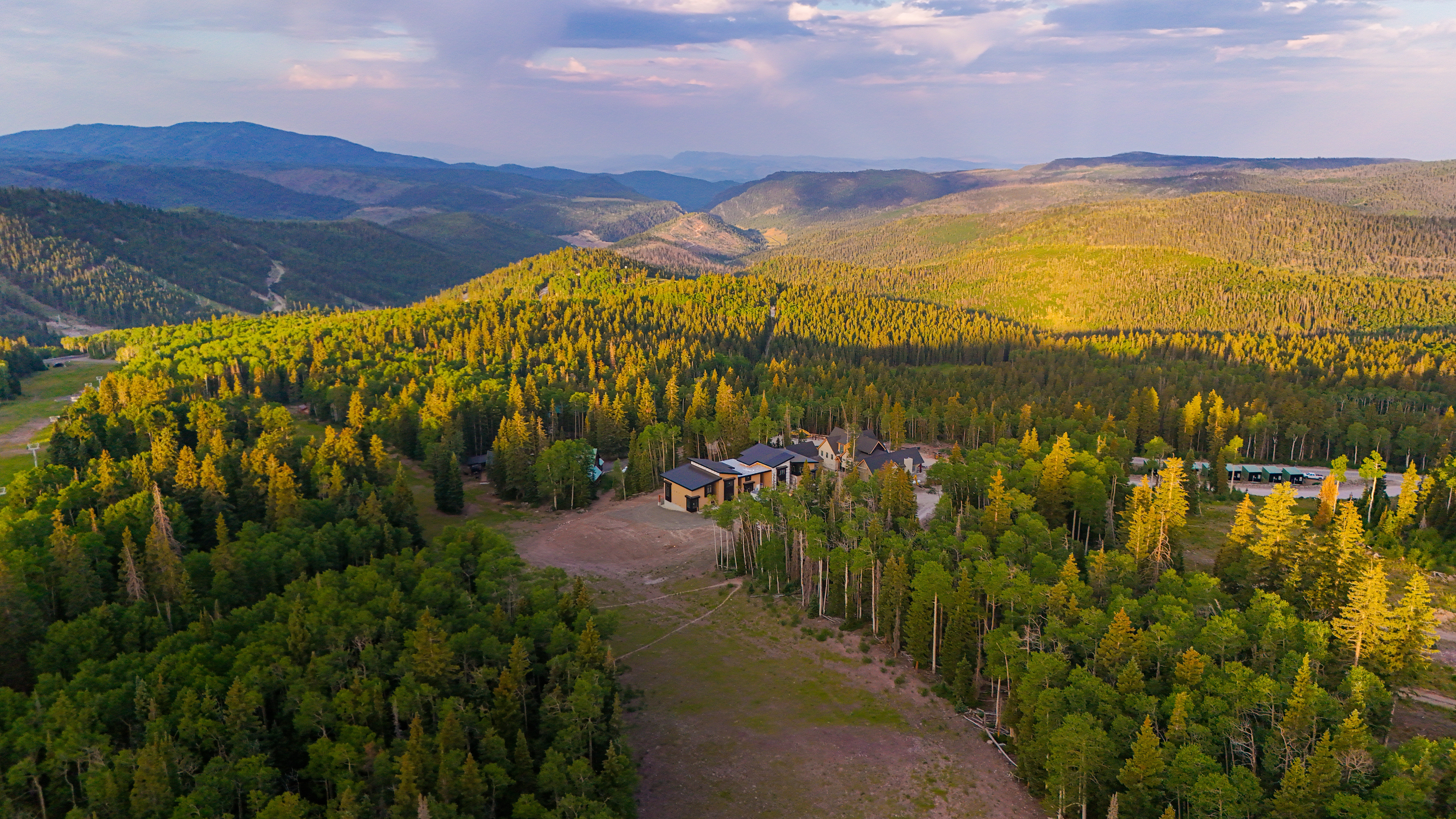 Extensive mountainous terrain surrounds a multi-structure property