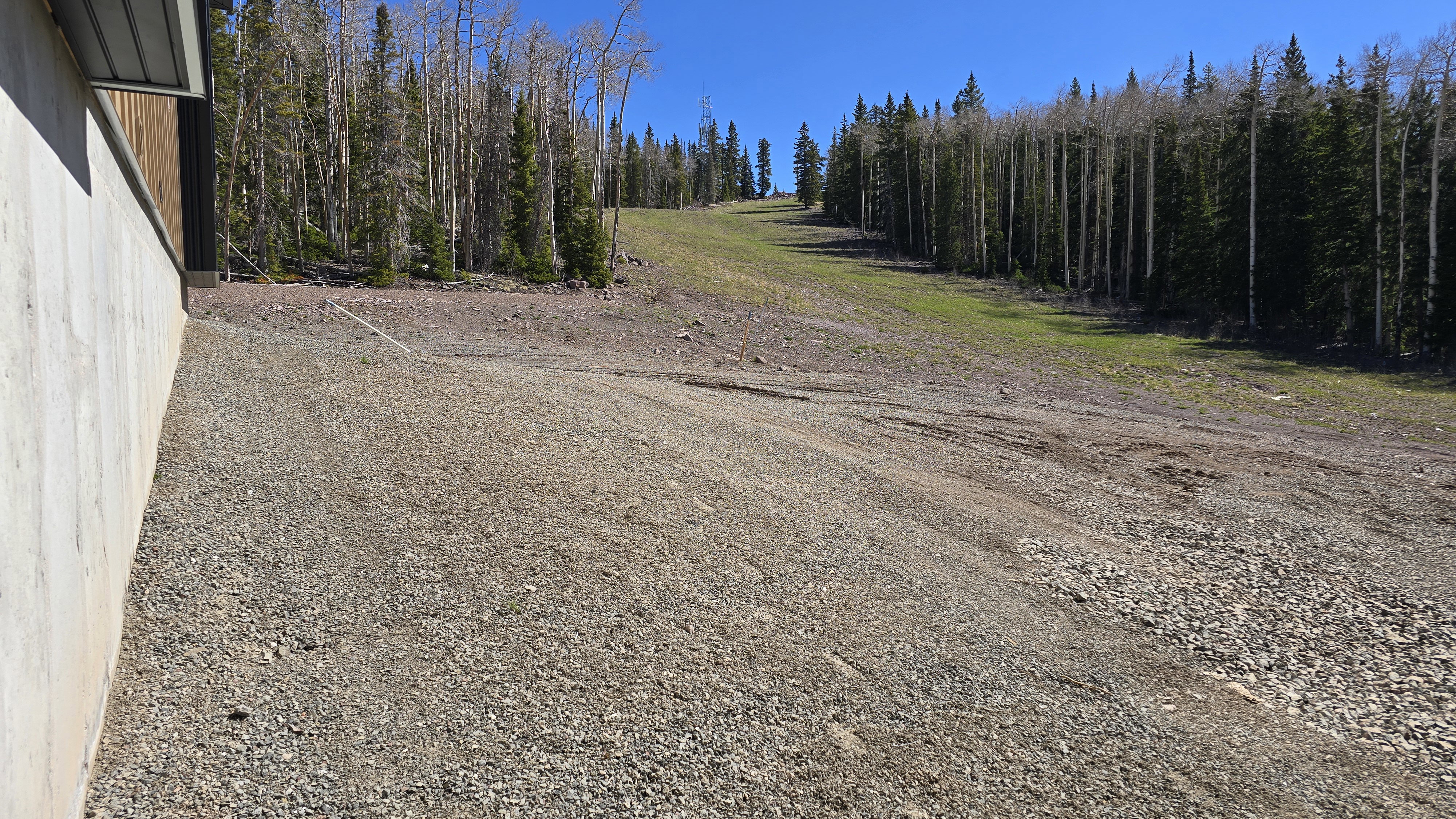 Expansive sloped grounds featuring a combination of gravel and natural terrain