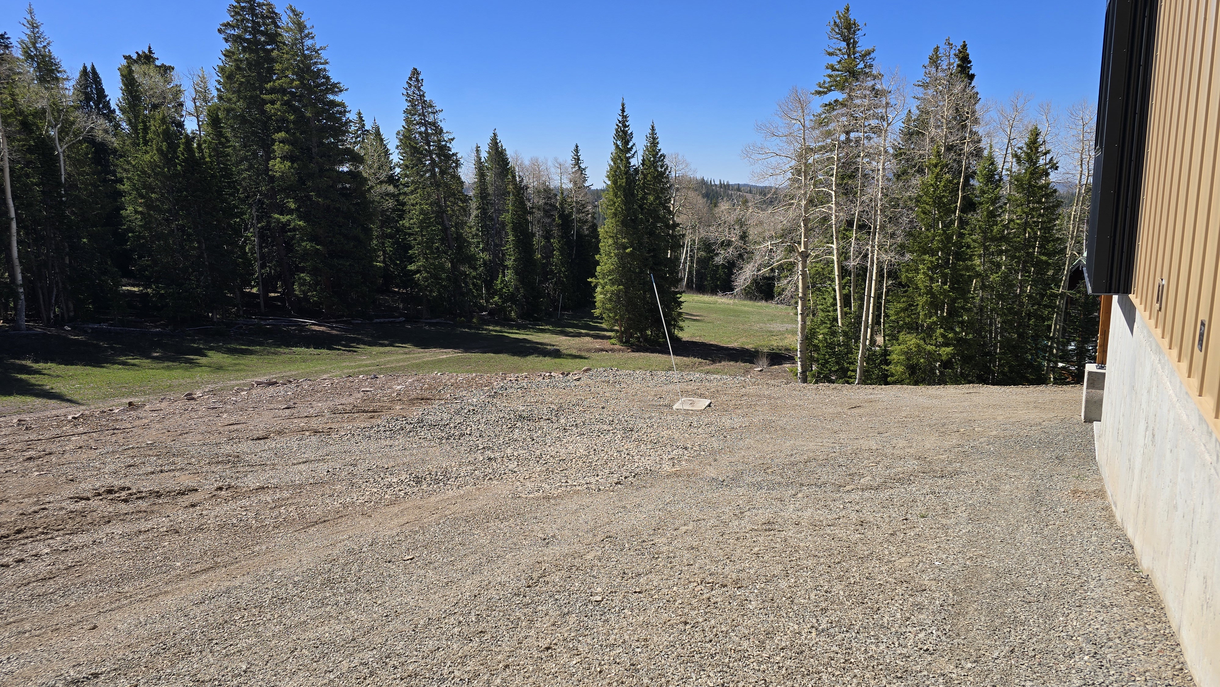 Gravel ground surface with a partial wood-paneled exterior and a concrete foundation