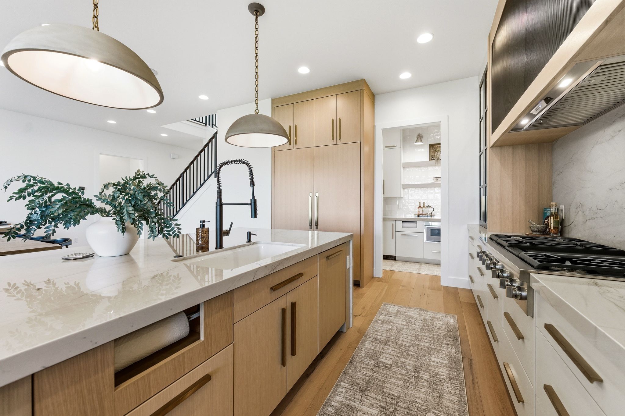 Contemporary kitchen featuring a large island with an undermount sink and a matte black faucet
