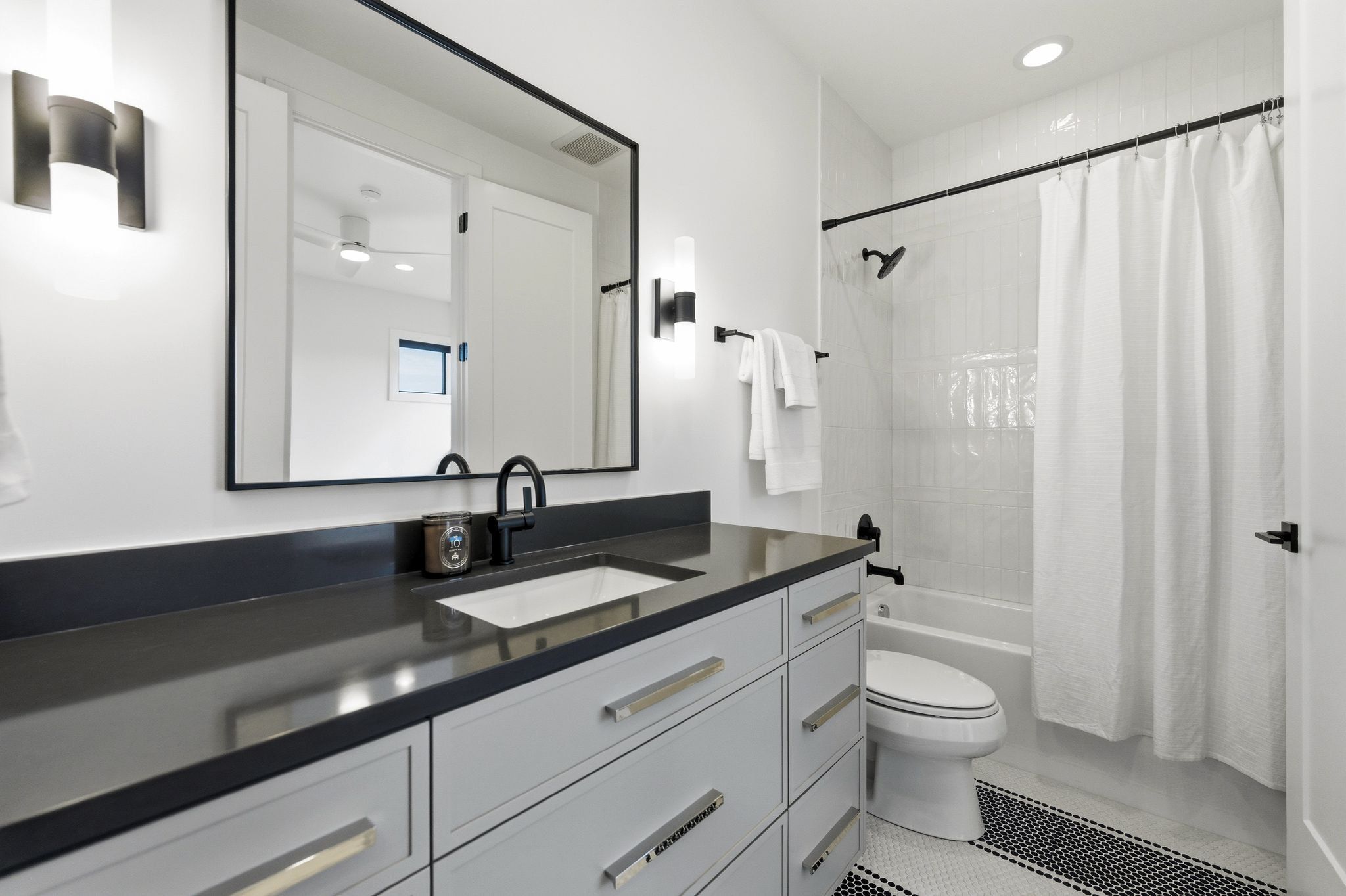 Bathroom featuring a dark countertop vanity with white cabinetry, a rectangular undermount sink, and matte black fixtures