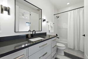 Bathroom featuring a dark countertop vanity with white cabinetry, a rectangular undermount sink, and matte black fixtures