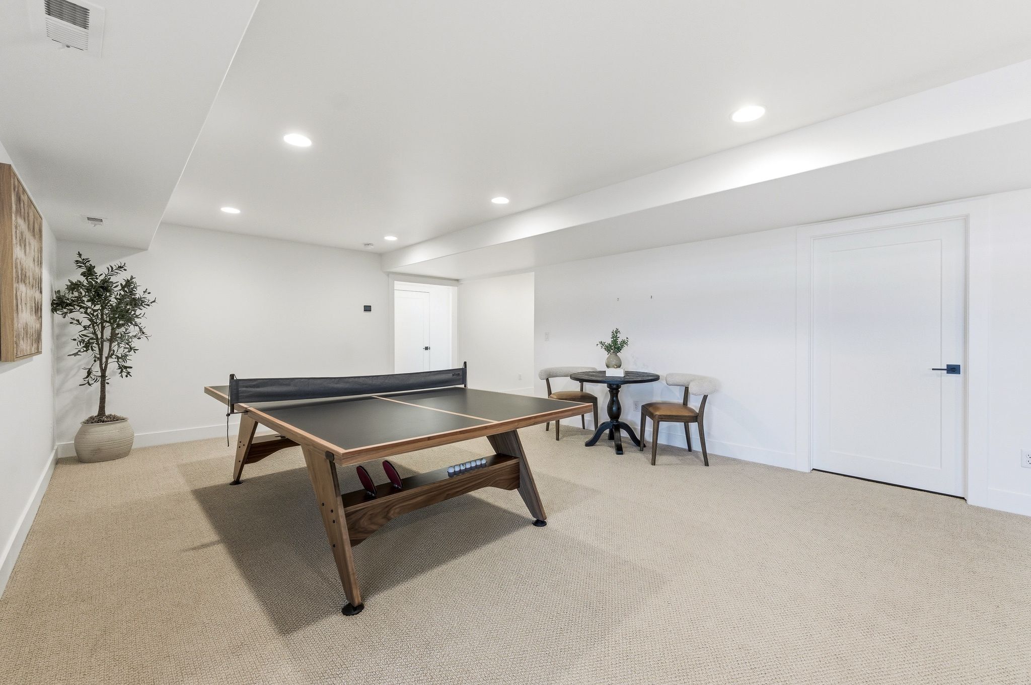 Spacious room featuring neutral carpeting, recessed lighting, white walls, and a built-in ceiling soffit