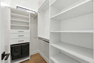Custom closet system featuring white shelving, integrated drawers with linear hardware, and wood-finish flooring