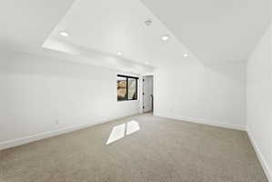 Carpeted room featuring recessed lighting, a white painted door, a window with black trim, and a tray ceiling