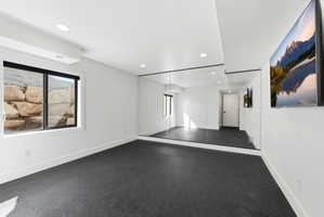 Versatile room featuring dark-toned resilient flooring, a full wall of mirrors, recessed lighting, and a single window