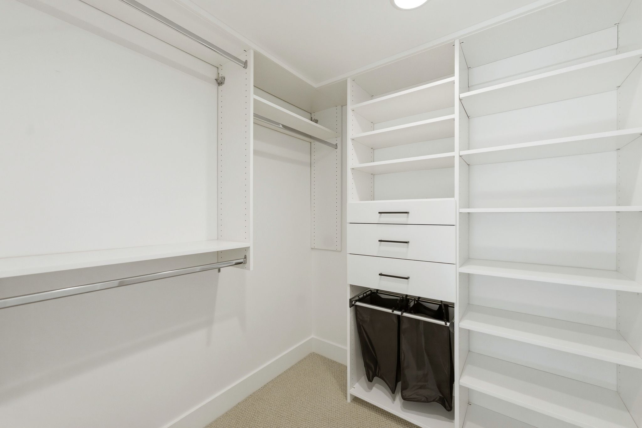 Custom closet system featuring multiple hanging rods, adjustable shelving, and integrated drawers with contemporary hardware