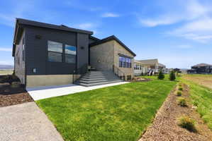 Contemporary exterior featuring dark horizontal siding, stone veneer accents, multi-pane windows, and a tiered concrete staircase with metal railings