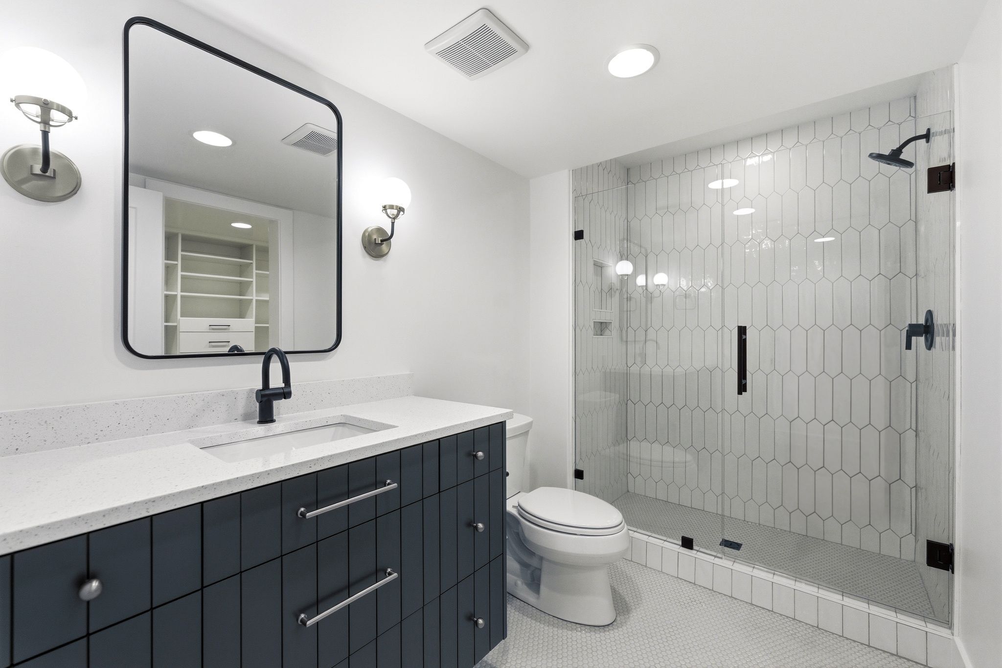 Contemporary bathroom featuring a dark blue vanity with a white countertop, an undermount sink, and a black framed mirror