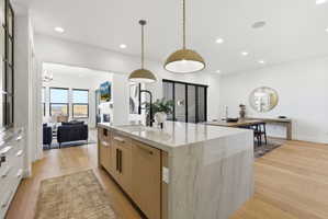 Gourmet kitchen island with waterfall countertop, integrated sink, and dual pendant lighting