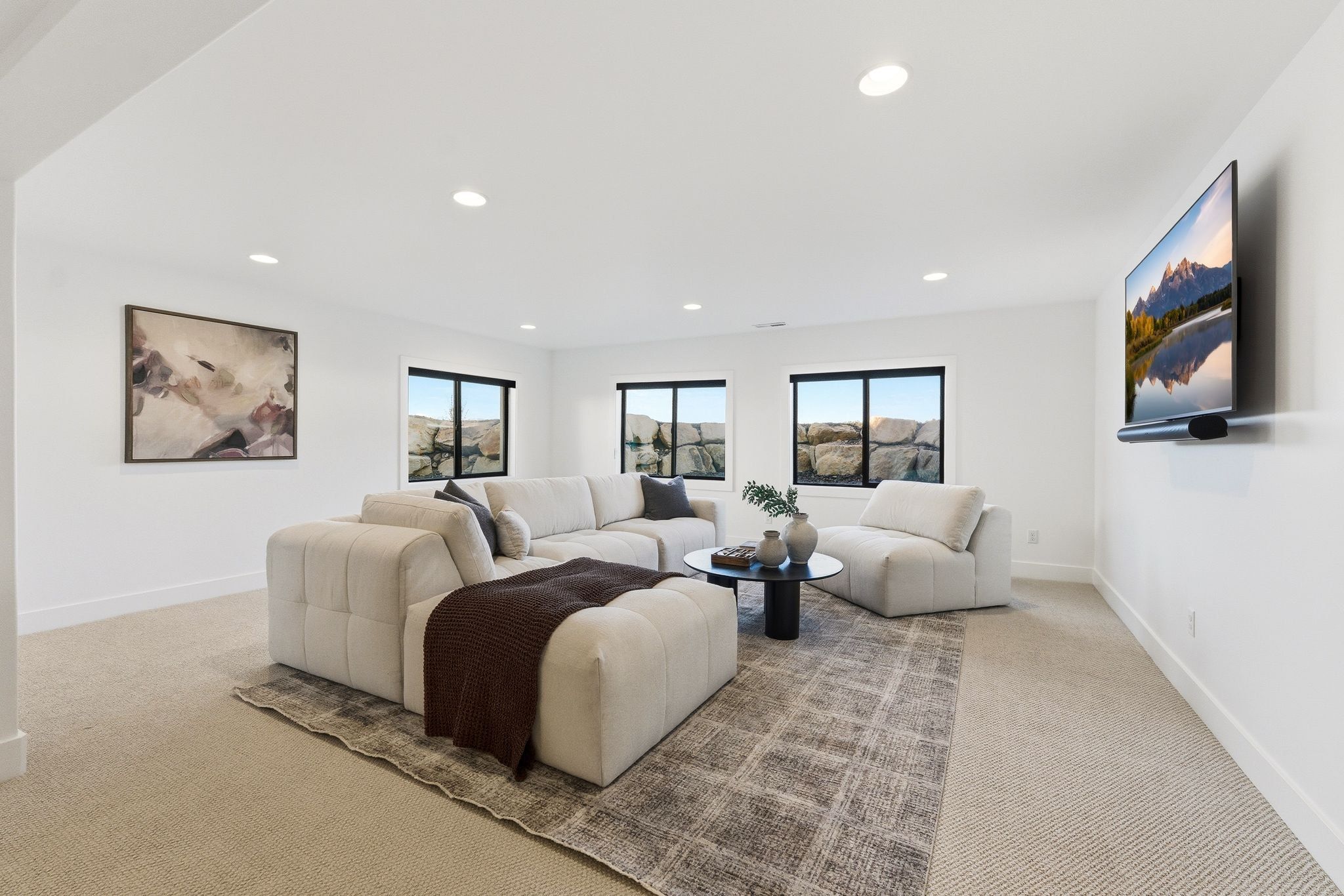 Spacious room featuring neutral carpet flooring, recessed lighting, and multiple windows with exterior rock formations