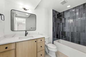 Bathroom featuring a light wood-finish vanity with a white countertop and integrated sink, a black-framed rectangular mirror, and matte black fixtures