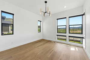 Expansive room featuring light wood-finish flooring, white walls, and a contemporary chandelier