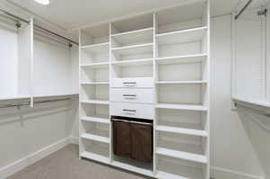 Custom closet system featuring white shelving, multiple hanging rods, three integrated drawers with dark hardware, and recessed ceiling lighting
