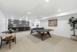 Expansive entertainment area featuring recessed lighting, light-toned carpeting, and a built-in wet bar with a distinctive tiled backsplash and integrated beverage refrigerators