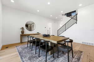 Bright dining area featuring light wood-finish flooring, recessed lighting, and white walls