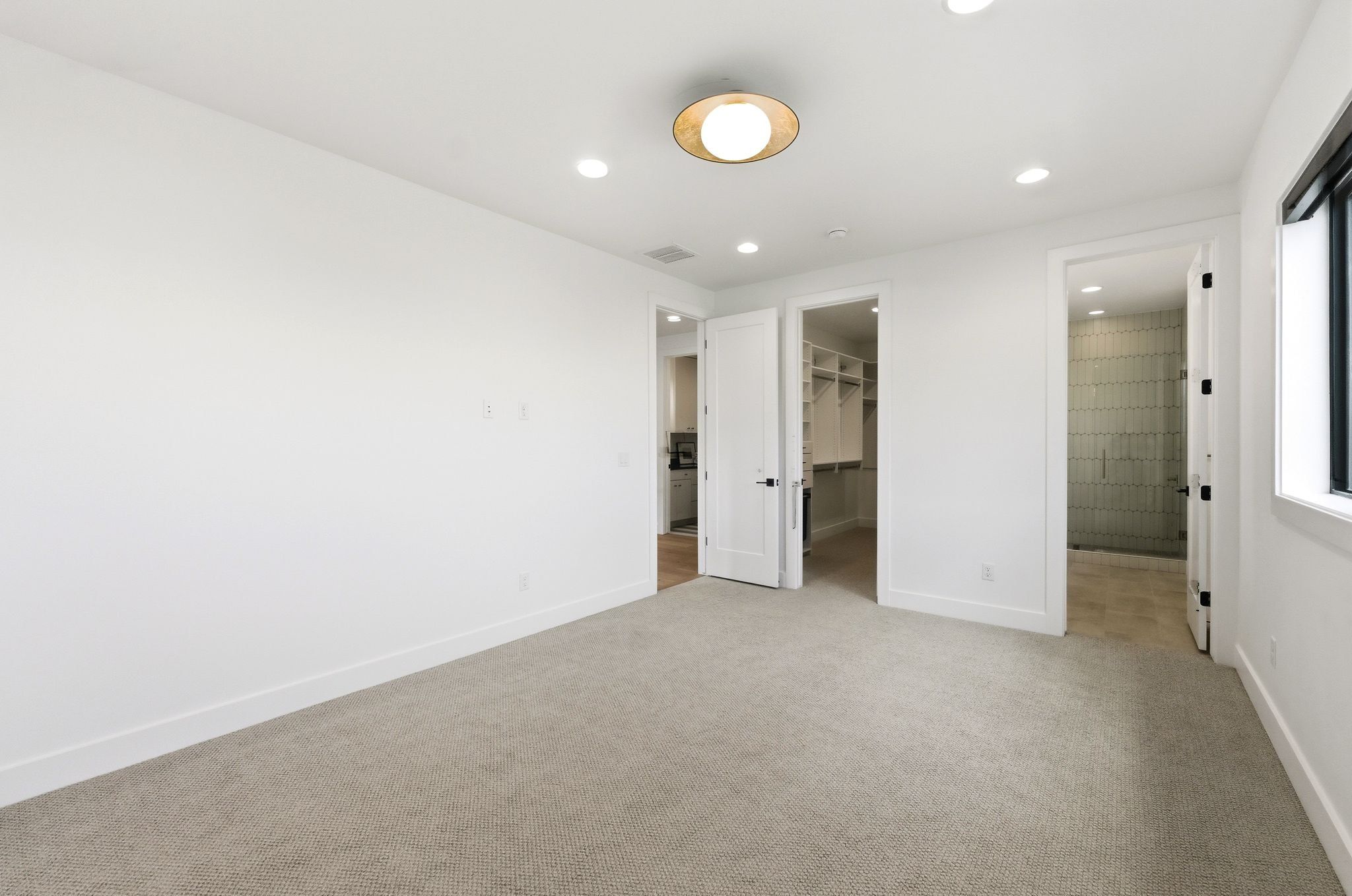 Carpeted room with white walls, a modern circular ceiling light fixture, recessed lighting, and a dark-framed window