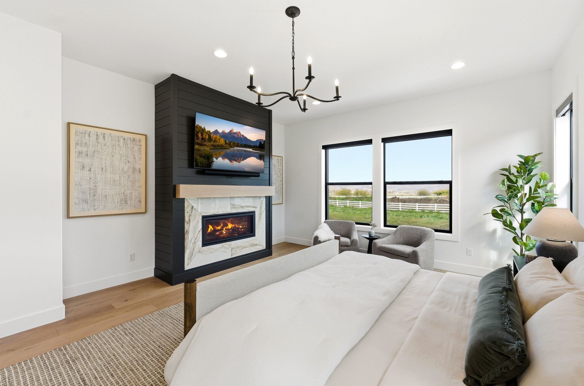 Spacious room featuring a contemporary fireplace with a stone surround, a prominent flat-screen television, and multiple large windows