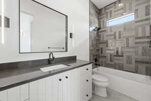 Bathroom featuring a white vanity with paneling, dark countertop, and matte black fixtures