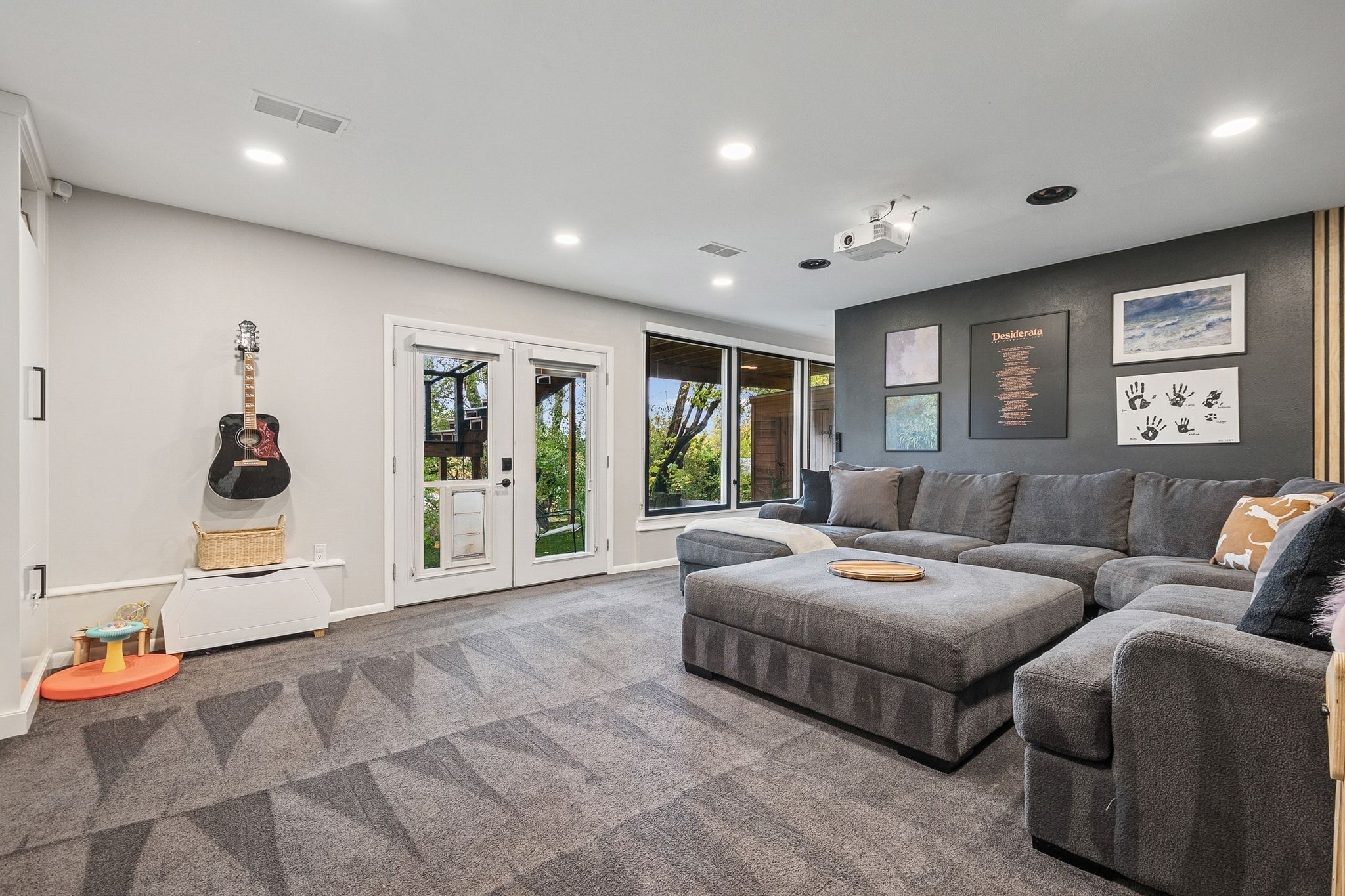 Expansive recreation room featuring a large sectional sofa, recessed lighting, and a wall-mounted projector