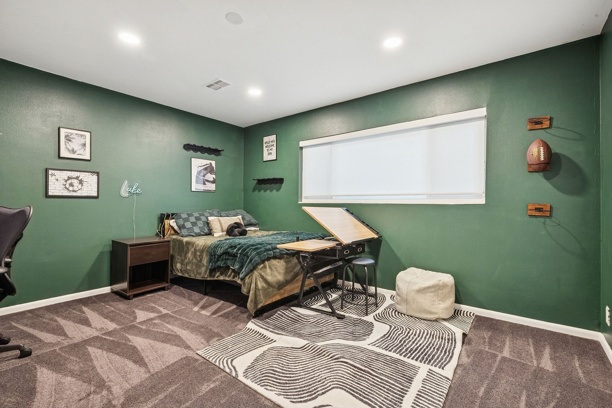 Carpeted room featuring recessed lighting, a window with a roller shade, and a built-in wall shelf