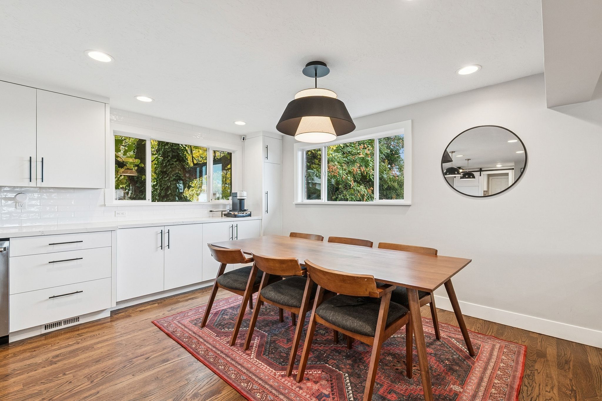 Open-concept kitchen and dining area featuring white cabinetry with dark hardware, a white subway tile backsplash, and recessed lighting
