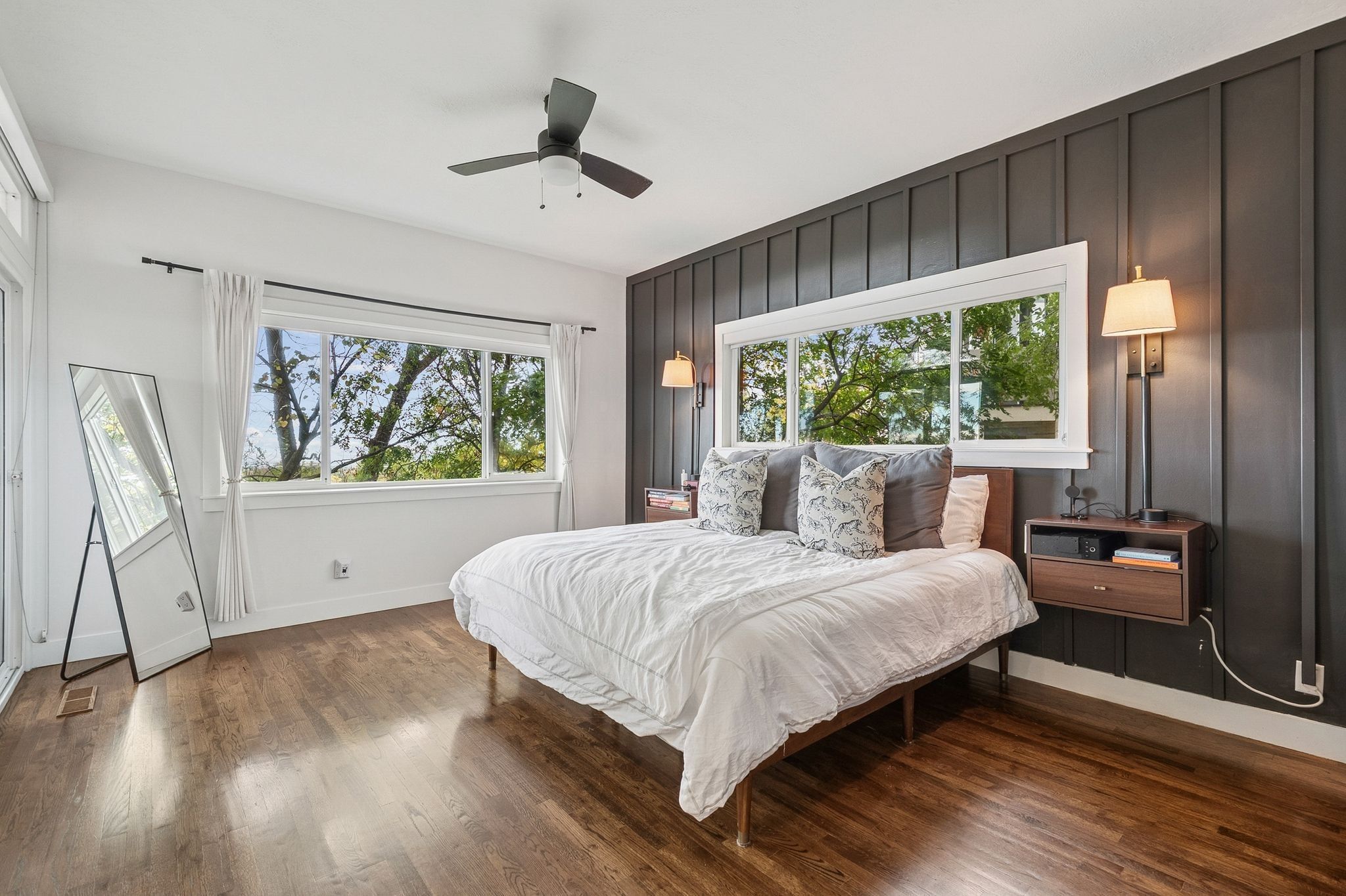 Bedroom featuring dark wood-finish flooring, white walls, and a prominent dark accent wall with vertical paneling