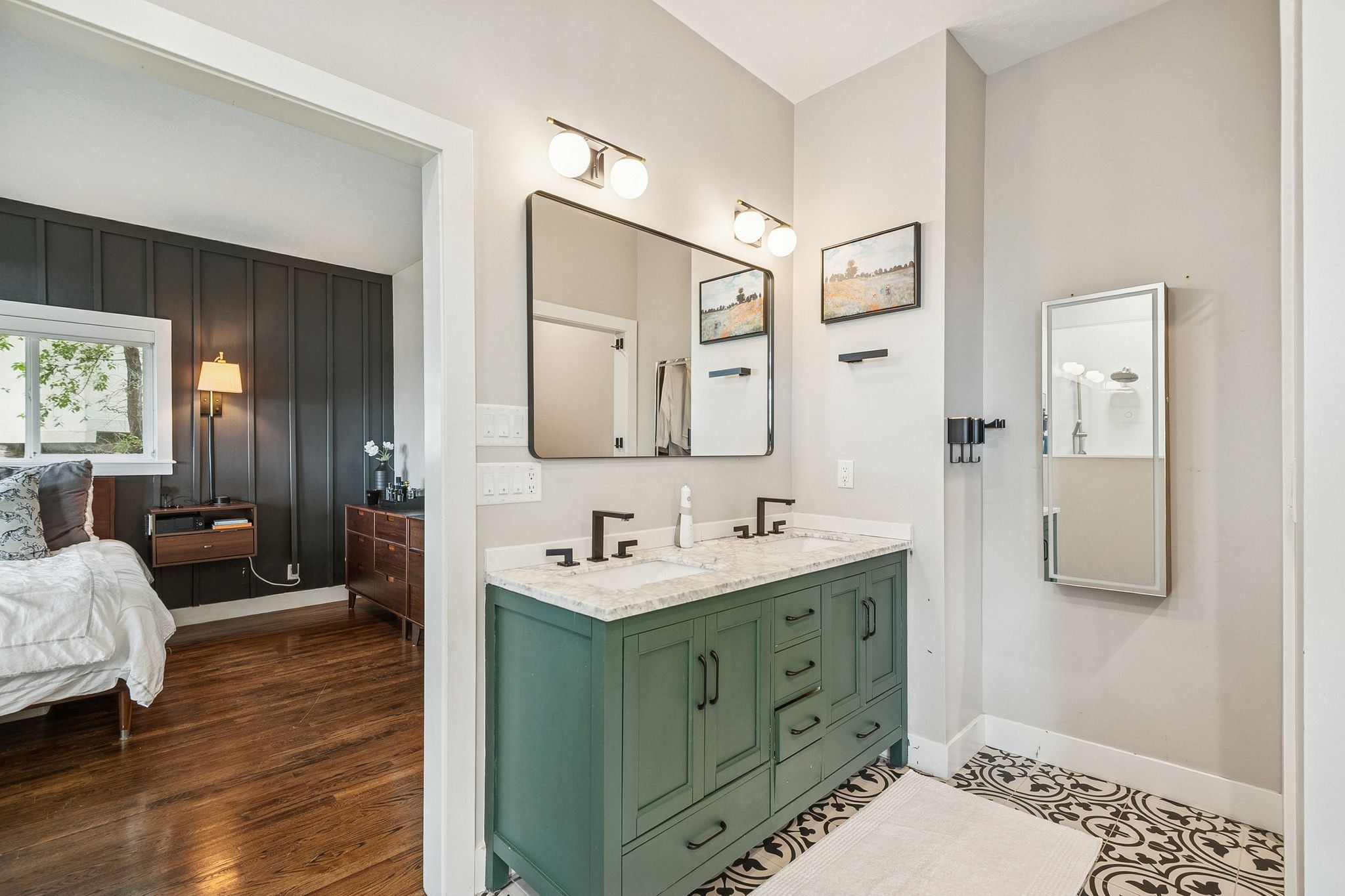 Bathroom vanity with dual sinks, a solid surface countertop, matte black fixtures, and a decorative tile floor