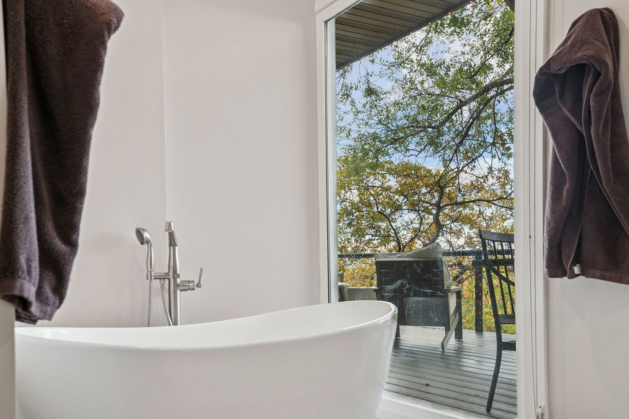 Freestanding soaking tub with a floor-mounted brushed nickel faucet and handheld shower