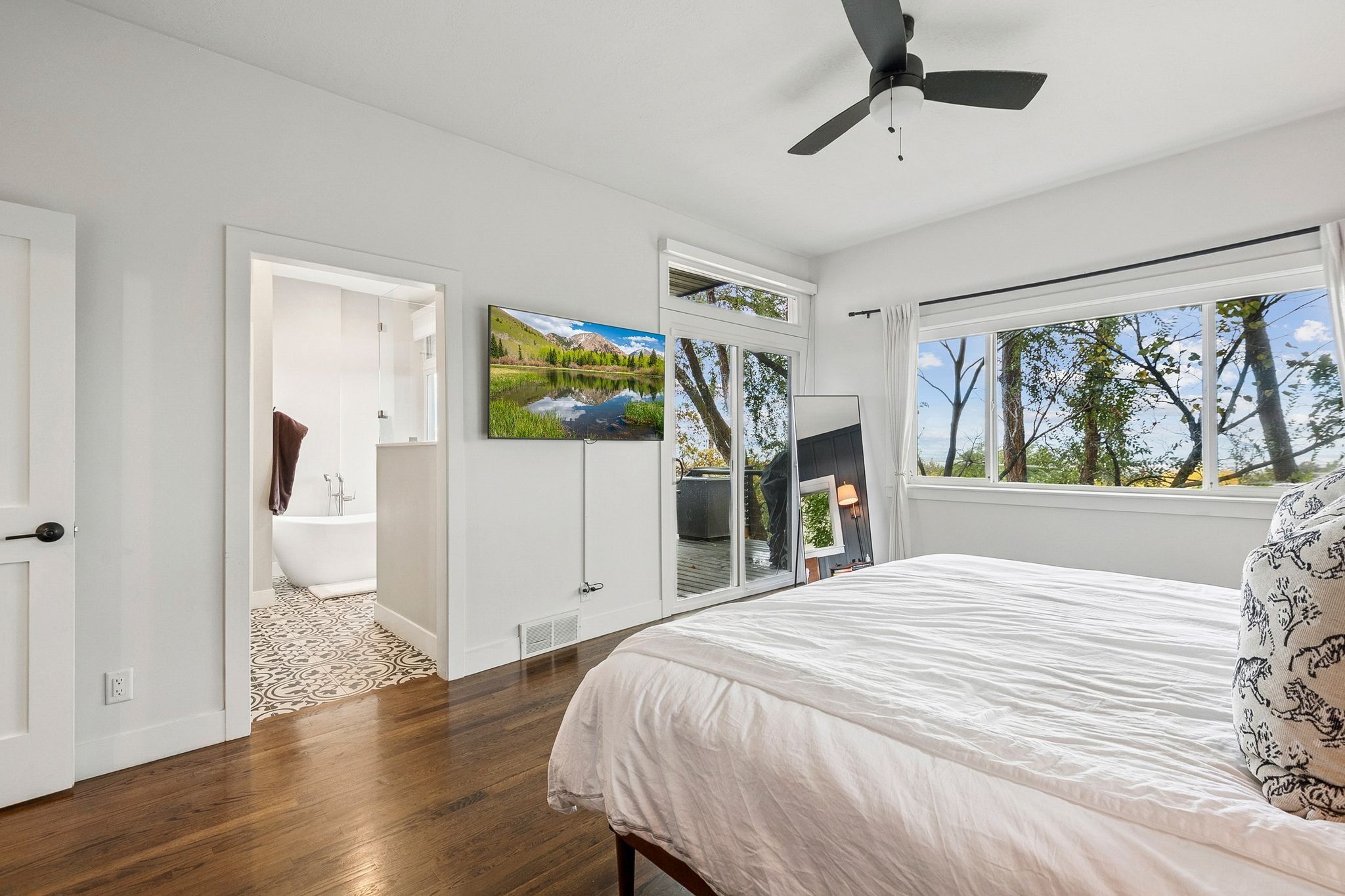 Bedroom with wood-finish flooring, a ceiling fan, and large windows