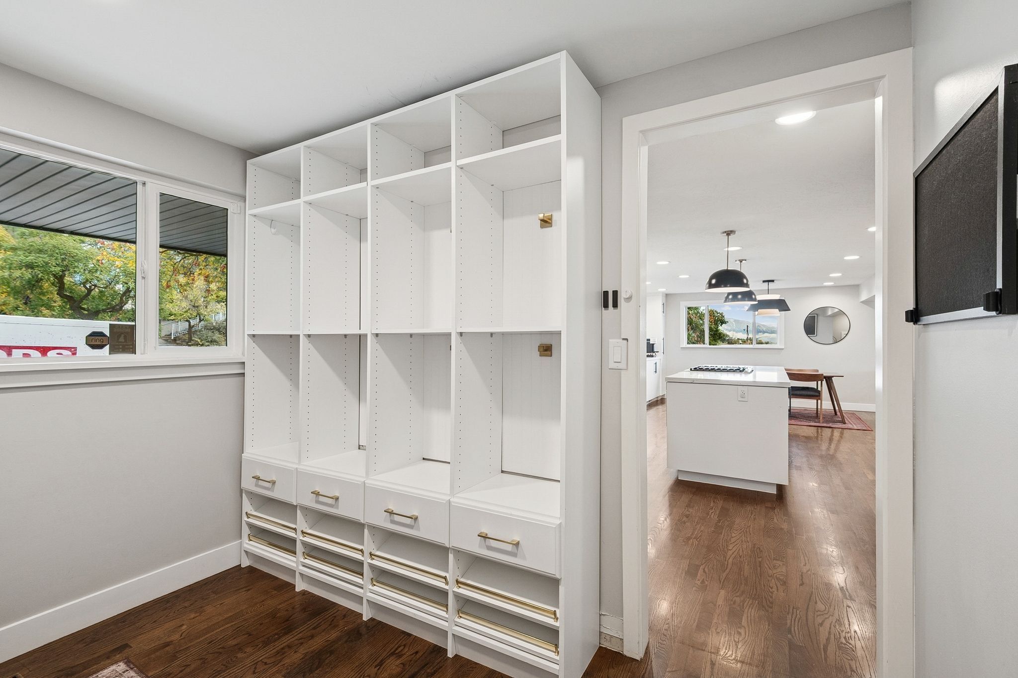 Custom built-in white shelving and drawers with gold-tone hardware, providing extensive storage