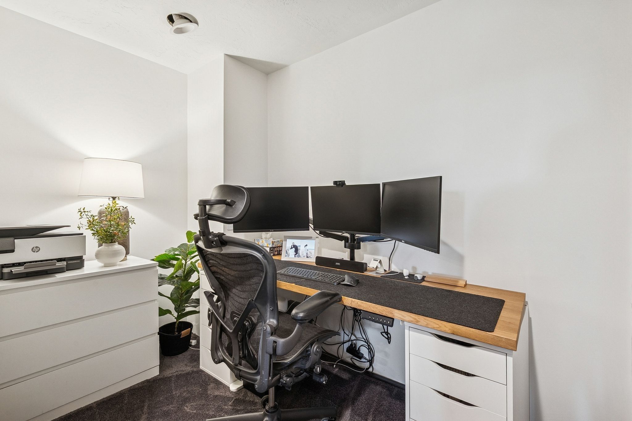 Dedicated workspace featuring a wood-finish desk surface, white storage units, and soft carpet flooring