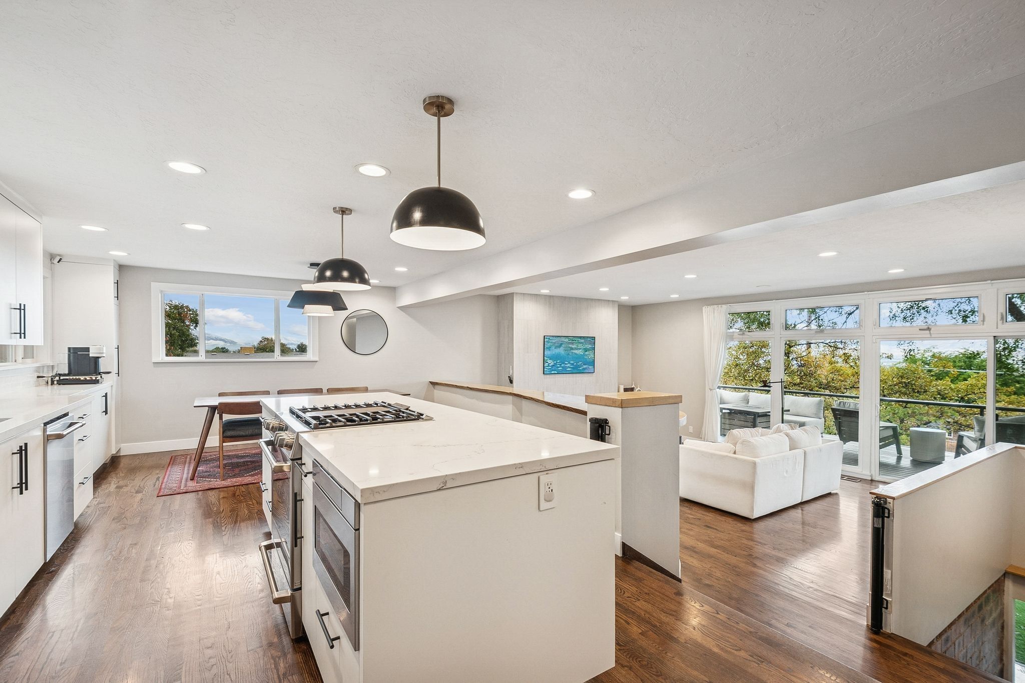 Open-concept kitchen featuring an island with a gas cooktop, white cabinetry, integrated appliances, and recessed lighting