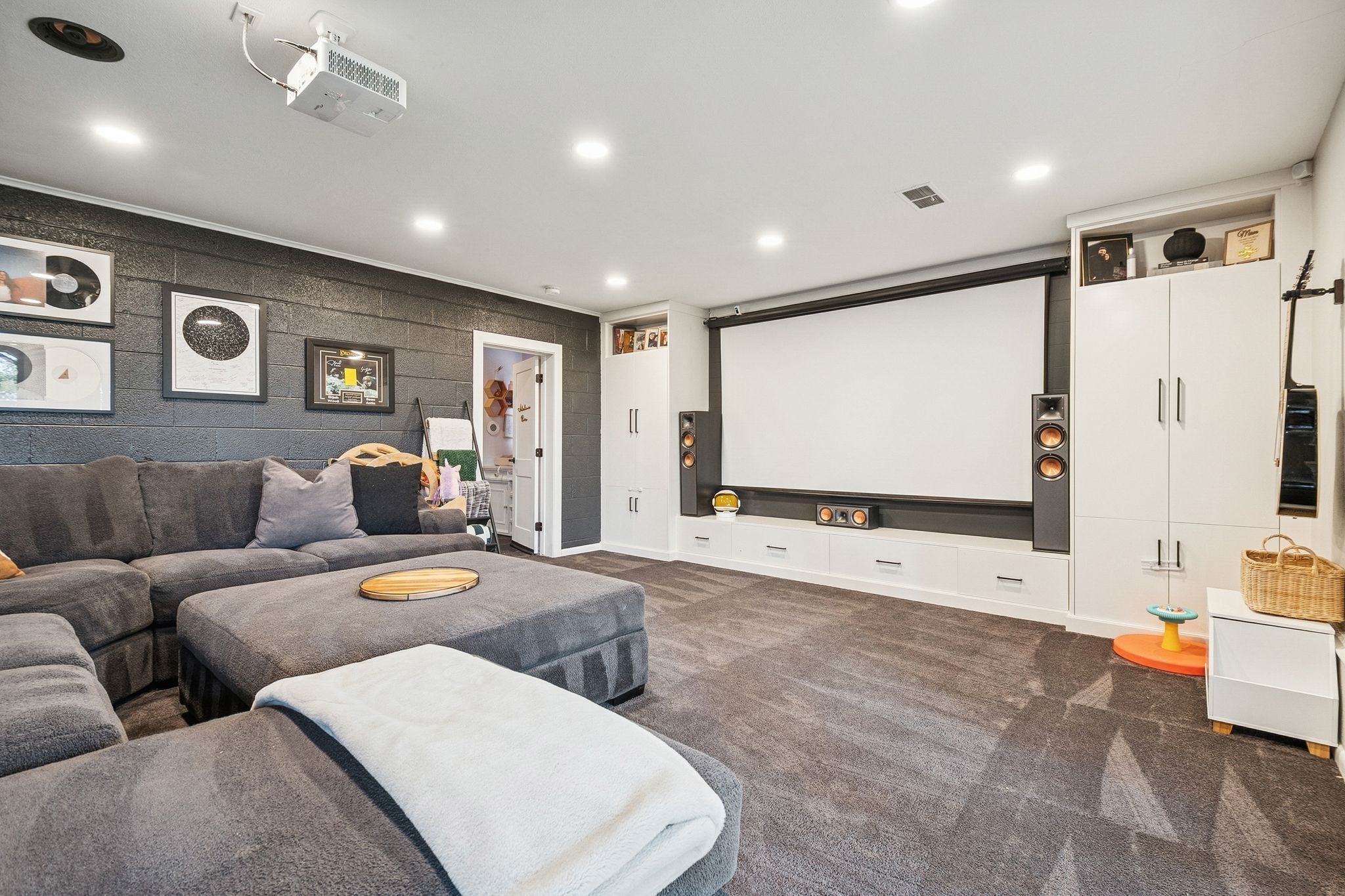 Dedicated media room featuring a large projector screen and ceiling-mounted projector