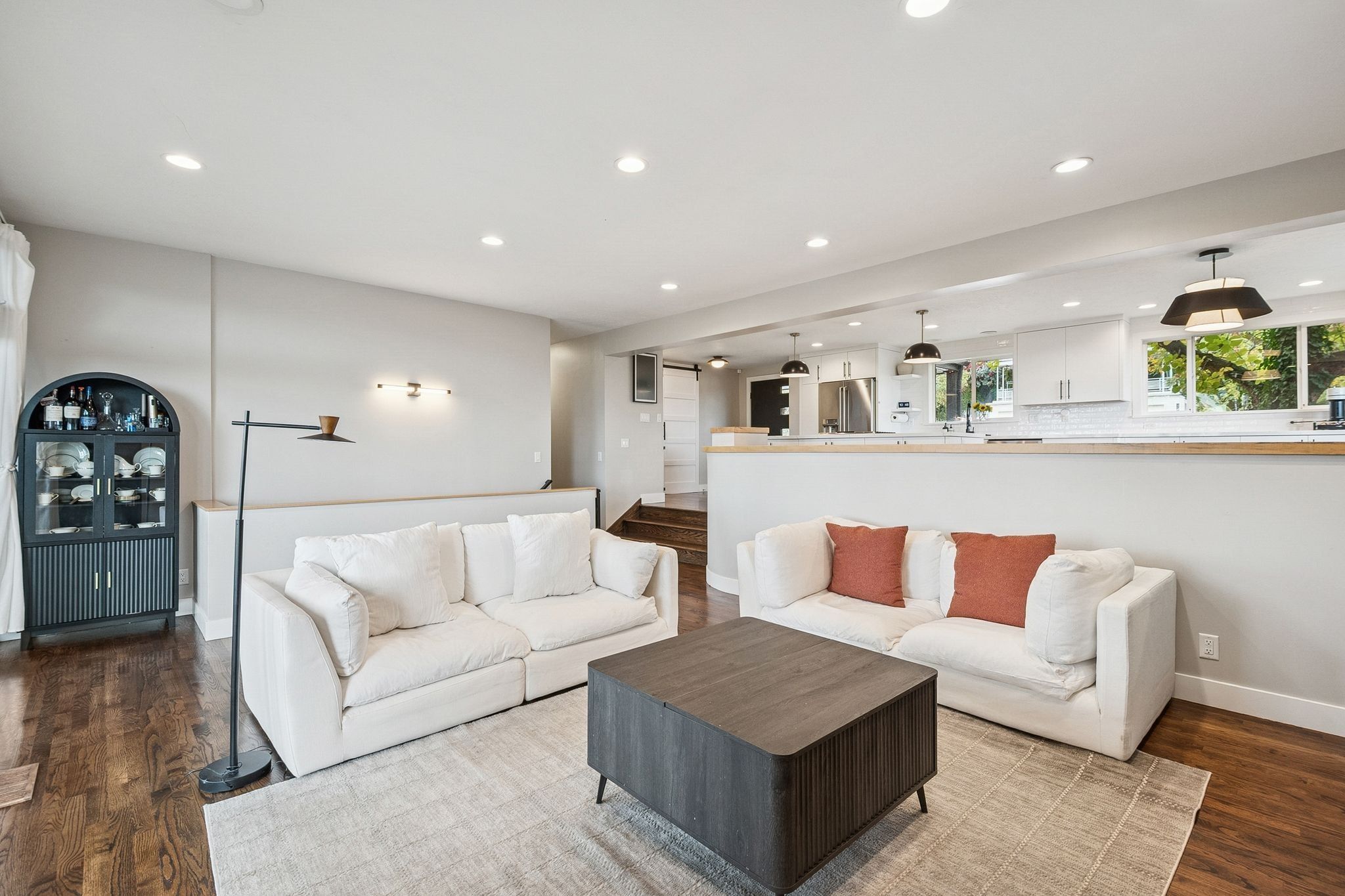 Open-concept living area with wood-finish flooring, recessed lighting, and a partial wall separating spaces