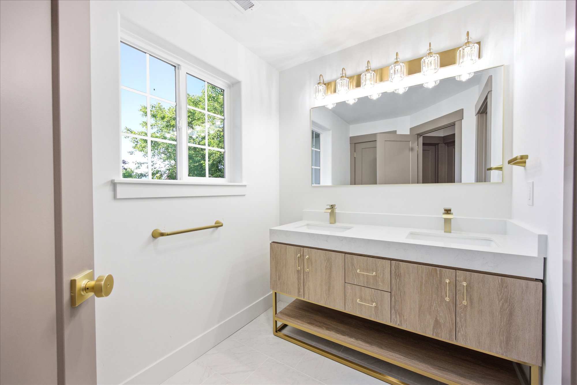 Modern vanity with dual rectangular undermount sinks, gold-tone fixtures, and wood-finish cabinetry