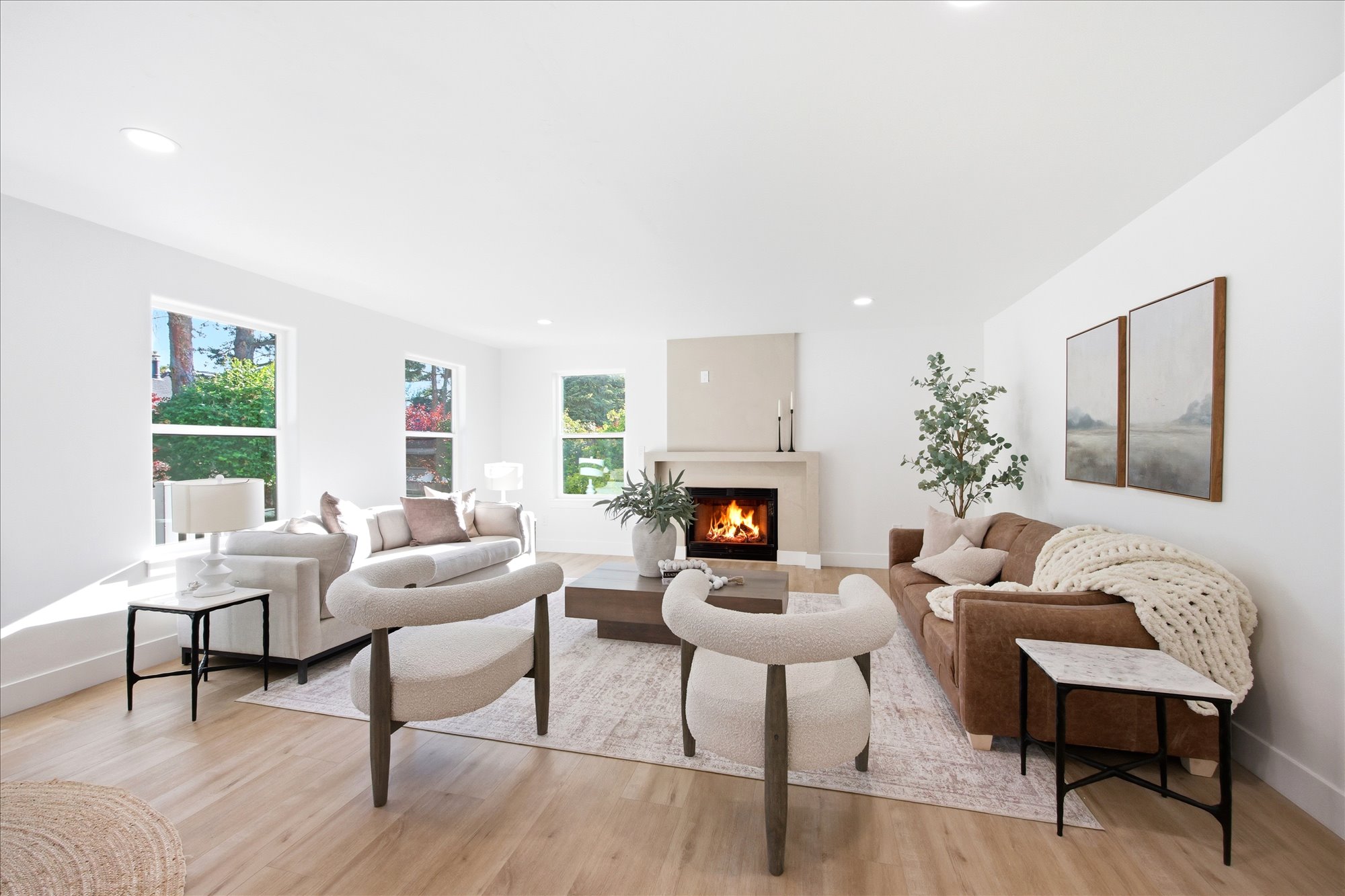 Spacious living area featuring light wood-finish flooring, recessed lighting, and a neutral-toned fireplace with a mantel