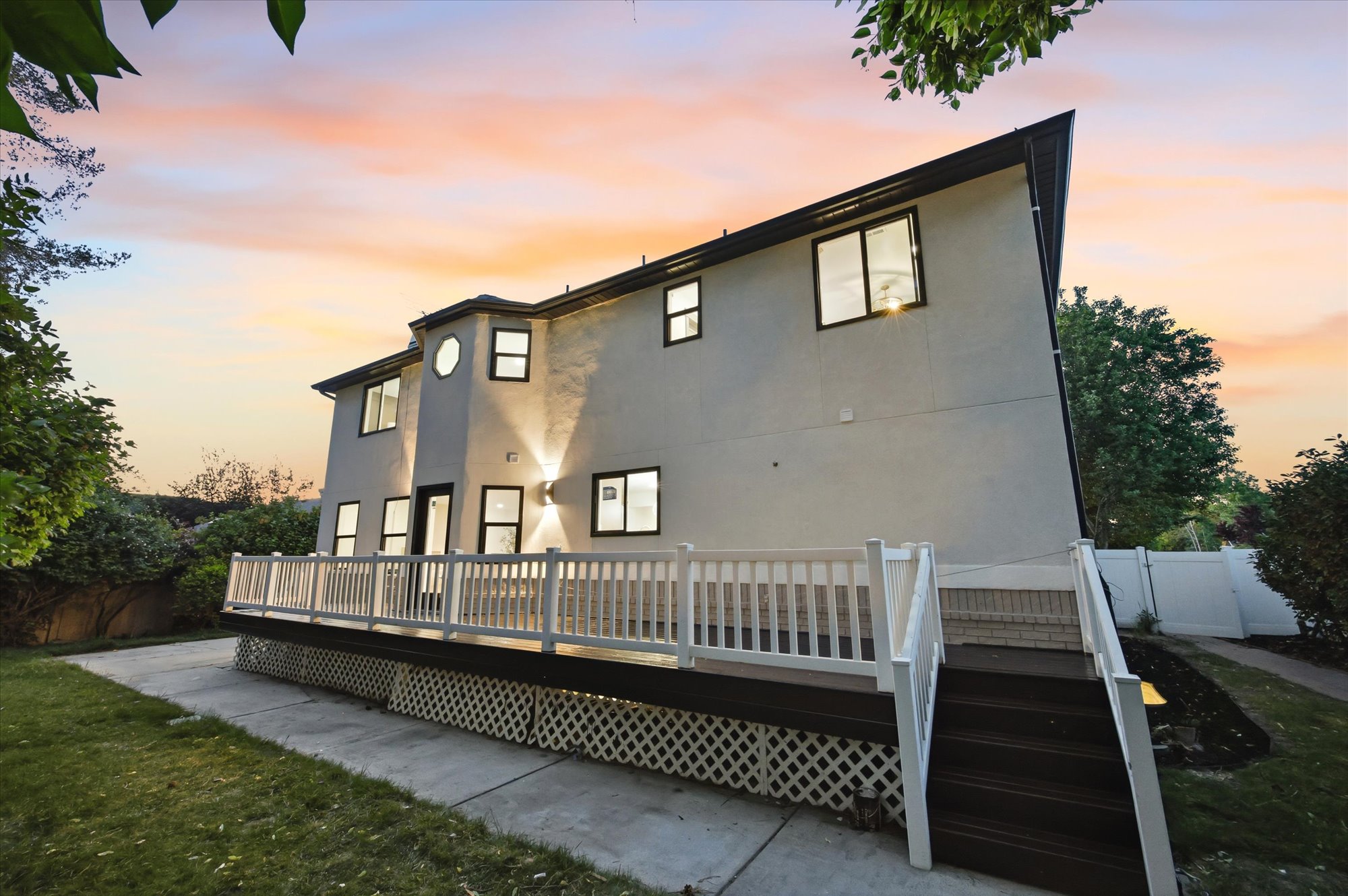 Contemporary stucco exterior featuring a multi-level deck with white railings and dark wood-finish stairs