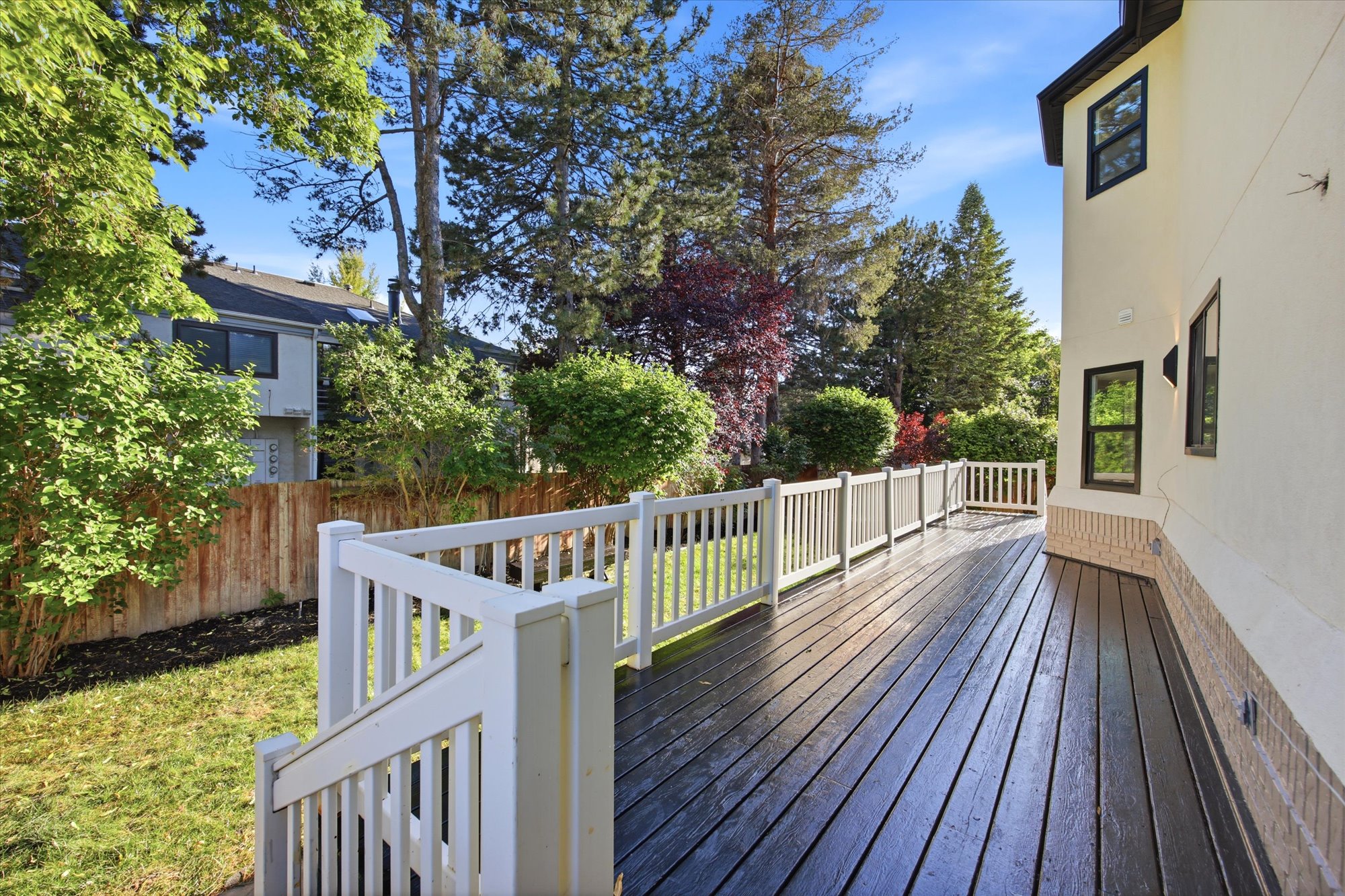 Spacious exterior deck with dark-stained wood-finish flooring and white perimeter railing