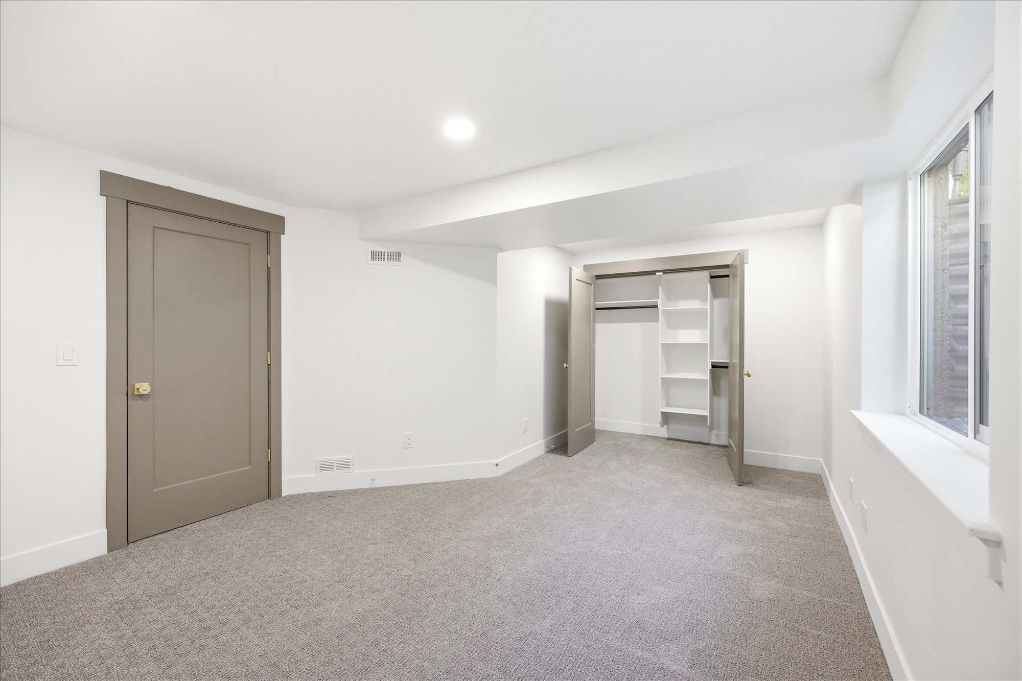 Neutral tone wall paint with crisp white trim, recessed lighting, and light gray patterned carpeting
