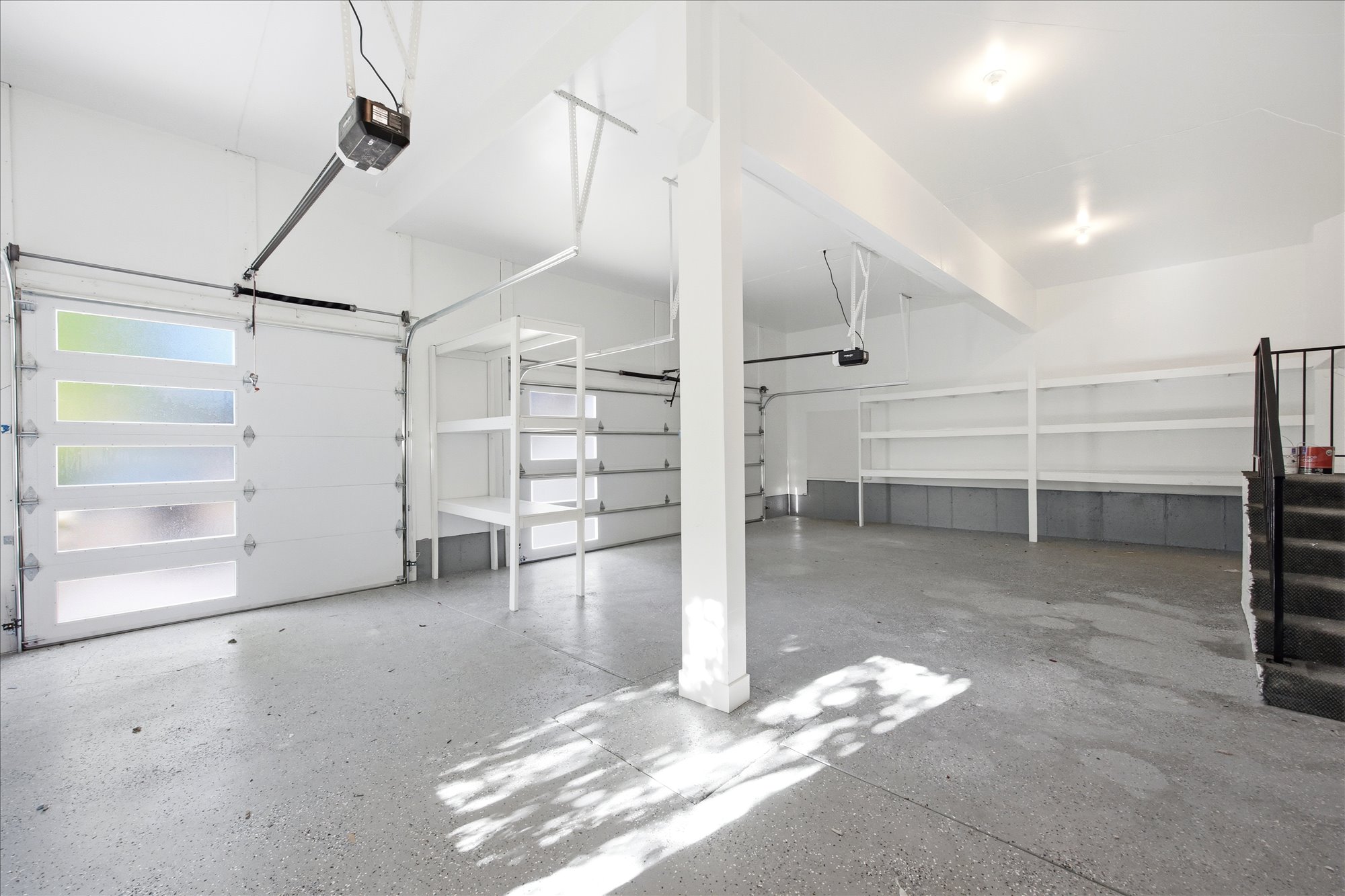 Spacious garage featuring two overhead doors, one with frosted glass panels